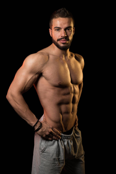 Muscular Athlete Flexing Muscles On Black Background - Foto, imagen