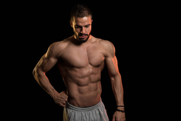 Muscular Man Flexing Muscles On Black Background - Φωτογραφία, εικόνα