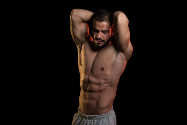 Muscular Athlete Flexing Muscles On Black Background - Photo, Image
