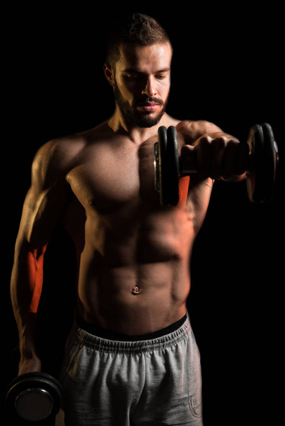 Man Exercise Shoulder With Dumbbells On Black Background - Фото, зображення