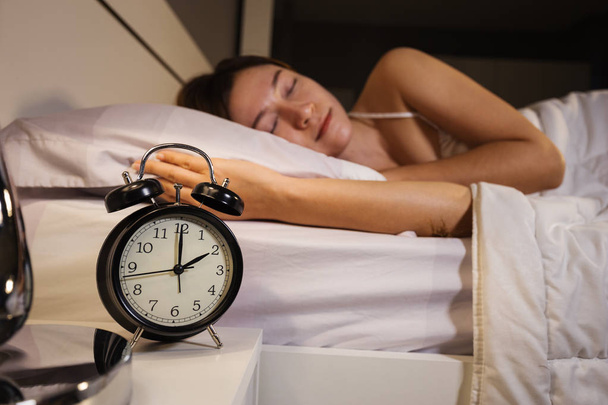 Ρολόι Εμφάνιση 2 η ώρα και η γυναίκα στον ύπνο στο κρεβάτι  - Φωτογραφία, εικόνα