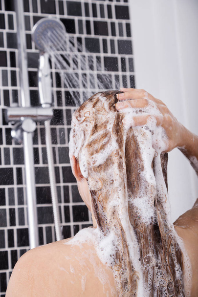 woman washing head and hair in the shower by shampoo, rear view - Fotoğraf, Görsel