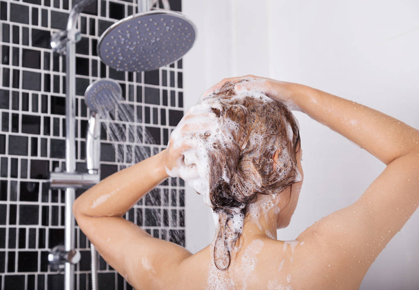 woman washing head and hair by shampoo, rear view - Foto, afbeelding