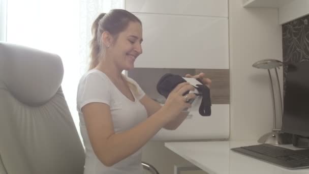 Mujer sonriente joven probándose los auriculares de realidad virtual. Filmación a 4K
 - Imágenes, Vídeo