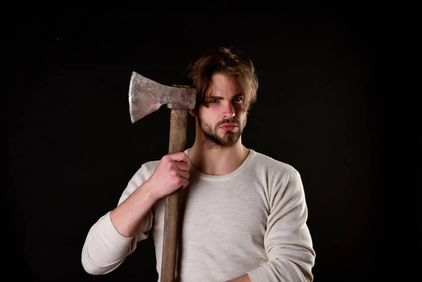 Bearded brutal guy with casual hairstyle holds old sharp axe - 写真・画像