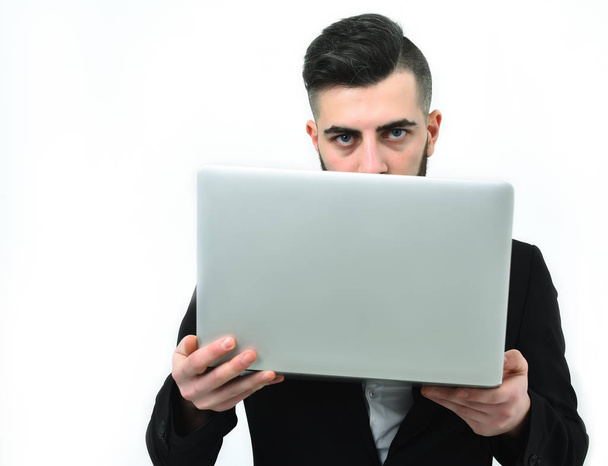Successful businessman with serious look holds white laptop - 写真・画像