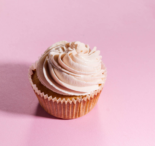 Closeup of tasty cupcakes with cream. Pink Background.  - 写真・画像