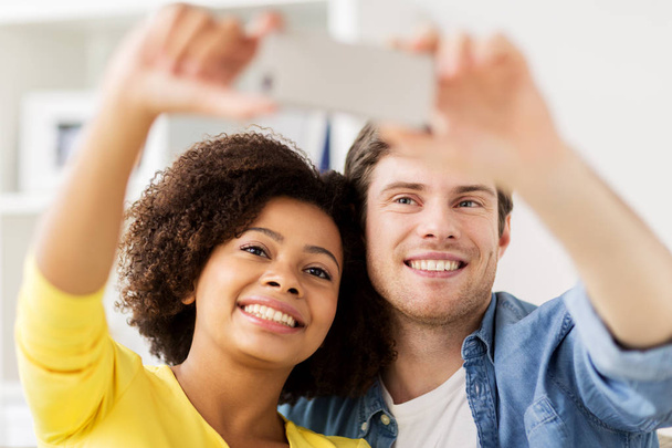 happy couple with smartphone taking selfie at home - Photo, image