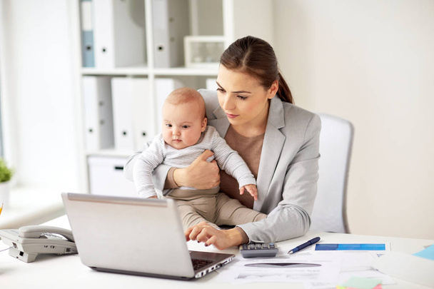 happy businesswoman with baby and laptop at office - Foto, imagen