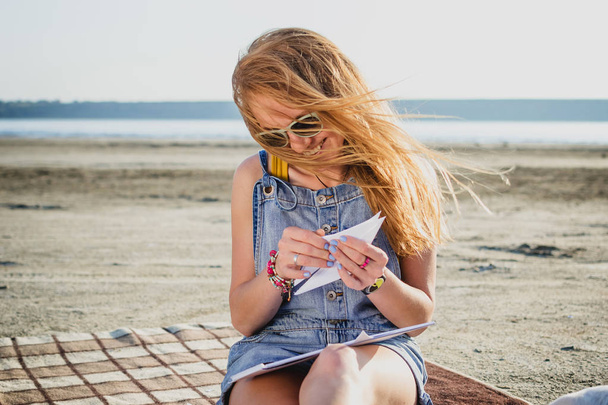 Young stylish hipster girl with origami on the beach - Photo, Image