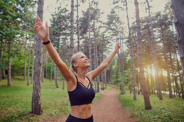 The sports girl her hands up in the forest. - Foto, imagen