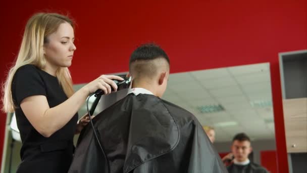 mladá kadeřnice oholí hlavy klienty salonu wellness centrum - Záběry, video