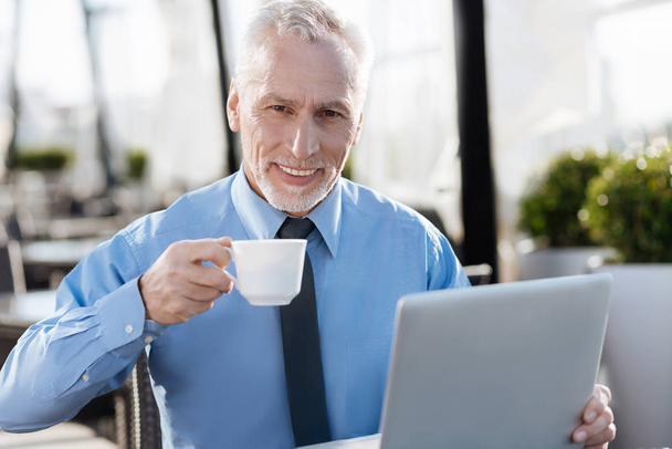 Senior man expressing positivity while drinking coffee - Foto, afbeelding