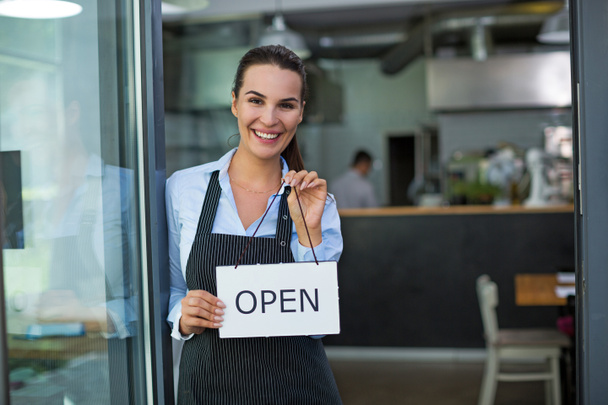 Woman holding open sign in cafe - Foto, Imagen