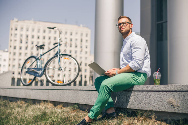 Business man with laptop and sport bike sitting in city. - Zdjęcie, obraz