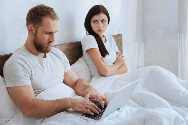 Man with laptop ignoring his frustrated girlfriend - 写真・画像