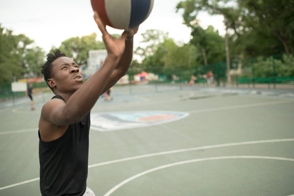 African american man plays on street basketball court. Real and authentic activity. - Photo, Image
