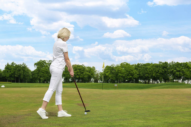 Beautiful young woman playing golf on course in summer day - 写真・画像