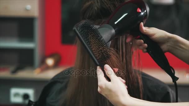 strzał z rąk fryzjerów, którzy wysusza włosy suszarką do włosów i grzebień - Materiał filmowy, wideo