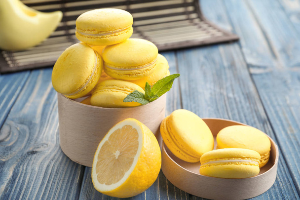 Box with tasty lemon macarons on wooden table, closeup - Foto, Imagen