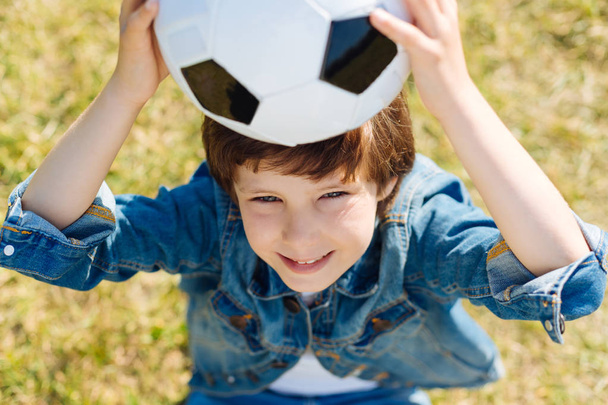 Attractive smart kid holding the ball up - Φωτογραφία, εικόνα