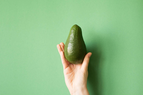 avocado in a hand of woman colored background. healthy food concept - Foto, Imagem