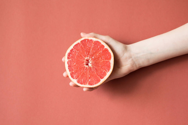 Hands of a young woman holding a red grapefruit. healthy food concept - Zdjęcie, obraz