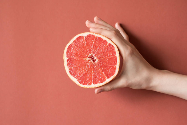 Hands of a young woman holding a red grapefruit. healthy food concept - Фото, зображення