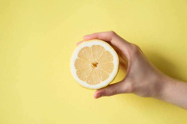 Lemon in woman's hand on a yellow background - Photo, image
