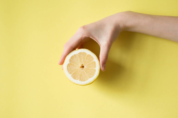 Lemon in woman's hand on a yellow background - 写真・画像