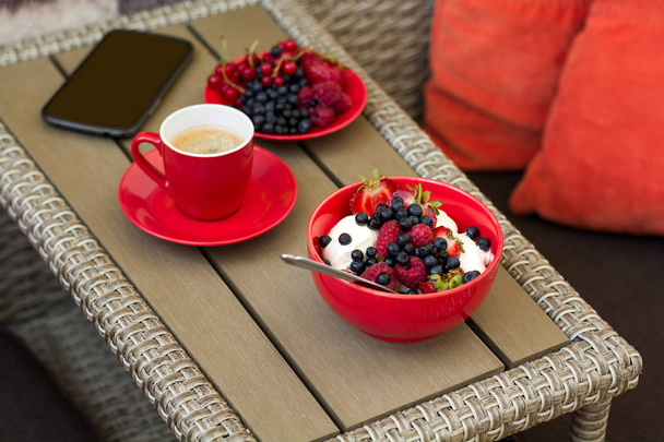 Healthy breakfast on garden furniture: cottage cheese with sour cream, strawberry, raspberry and blueberry, espresso and plate of fresh ripe berries - Fotó, kép