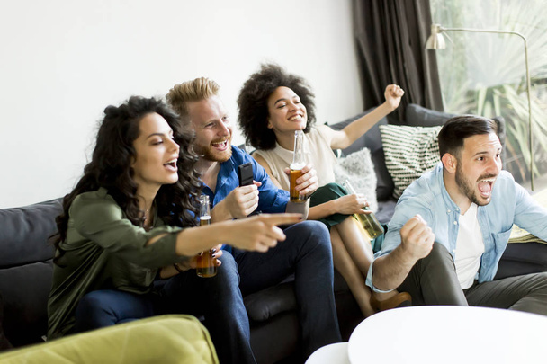 Grupo de amigos viendo televisión, bebiendo sidra y divirtiéndose
 - Foto, imagen