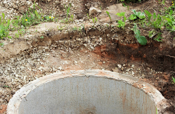 Колодец для добычи воды. Строительство деревенского колодца для добычи воды с помощью нескольких бетонных колец, уложенных в землянку
 - Фото, изображение