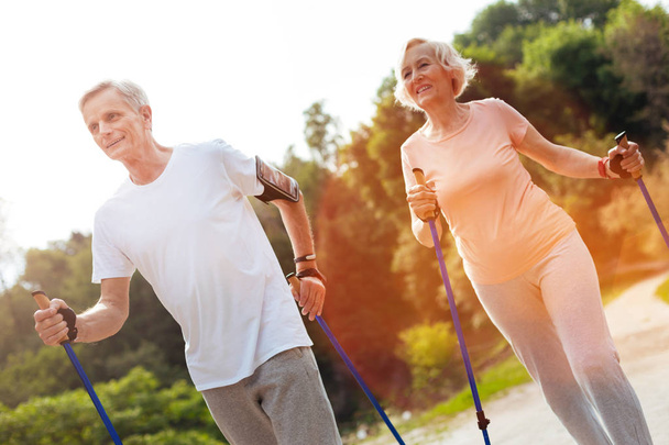 Delighted elderly couple practicing Nordic walking - Fotografie, Obrázek