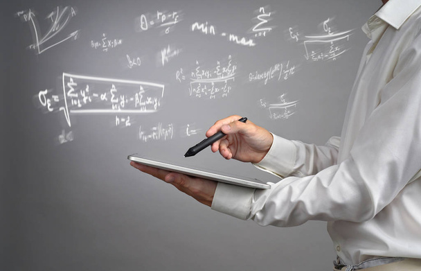 Man scientist or student holding tablet PC and working with various high school maths and science formulas. - 写真・画像