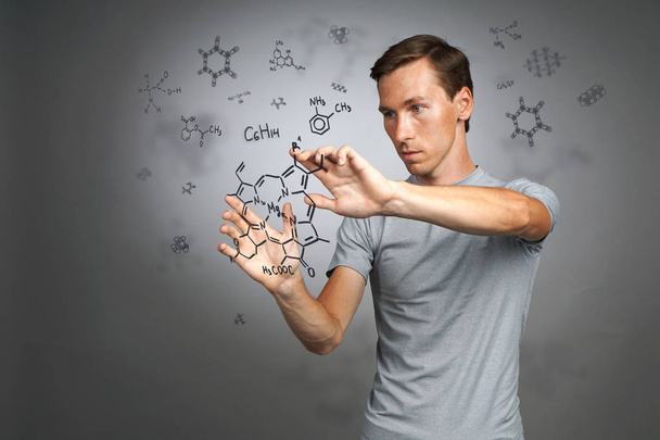 Man scientist in white shirt working with chemical formulas on gray background. - Foto, Imagen