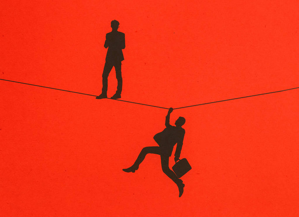 Мужчины силуэты стоят и держатся за веревку на красном фоне. Концепция балансировки
.  - Фото, изображение