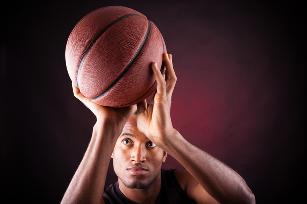 Portrait of a young male basketball player against black backgr - Фото, изображение