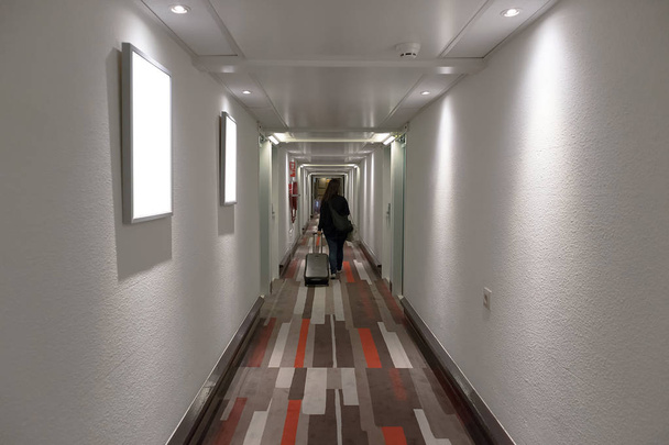 スーツケースを持ってホテルの廊下を歩いて女の子. - 写真・画像