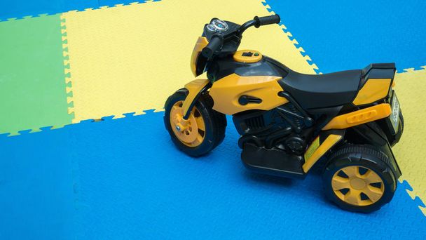 Gros plan du jouet de moto jaune sur le sol en caoutchouc avec espace de copie à l'aire de jeux
. - Photo, image
