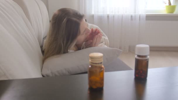 Young sick woman got flu and taking pills in bottle from table at living room - Video, Çekim