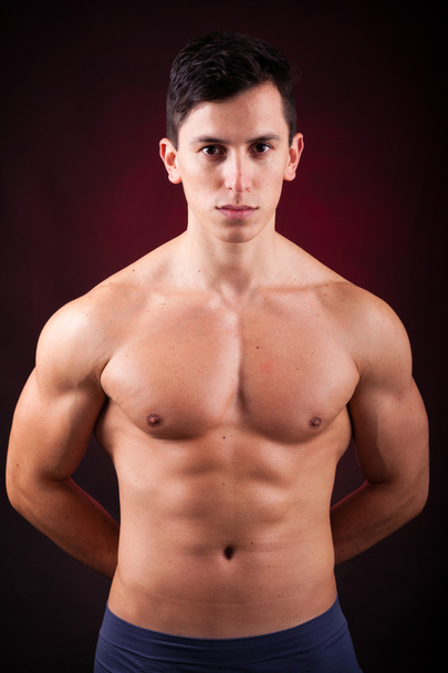 Portrait of a young muscular man against black background - Photo, Image