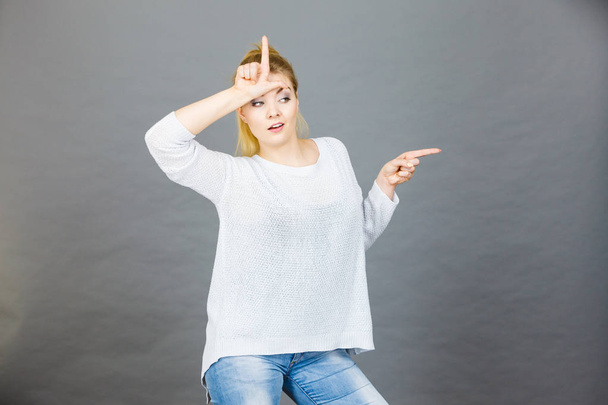 Woman showing loser gesture with L on forehead - Foto, Imagem