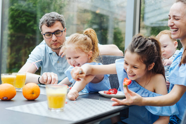 Familia feliz comiendo fruta fresca desayuno - Foto, imagen
