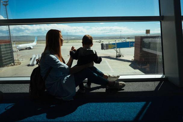 Little boy and his mother sitting in an airport - Photo, Image