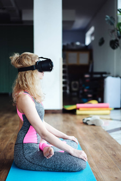 Woman in yoga class with VR headset - 写真・画像