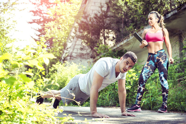 Female personal trainer and her client doing push ups outdoor - Photo, Image