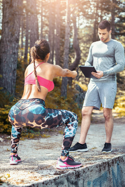 Female squats outdoor with personal trainer - Φωτογραφία, εικόνα