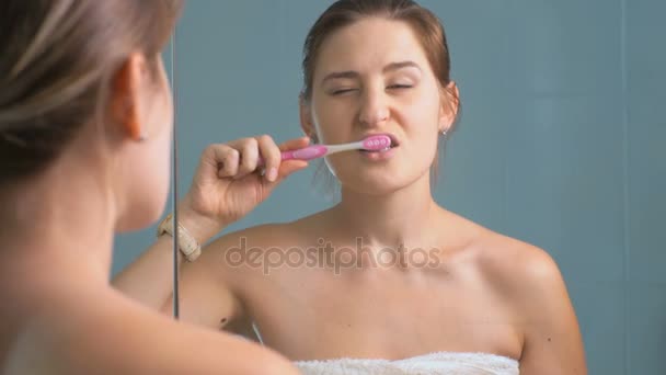 4K footage of young sleepy woman brushing teeth and looking at wristwatch - Footage, Video