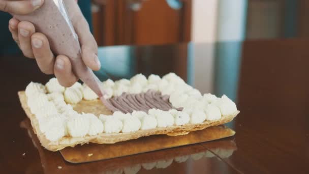 Gebak cook mannelijke handen knijpt crème uit de mouw op koek laag te vullen - Video